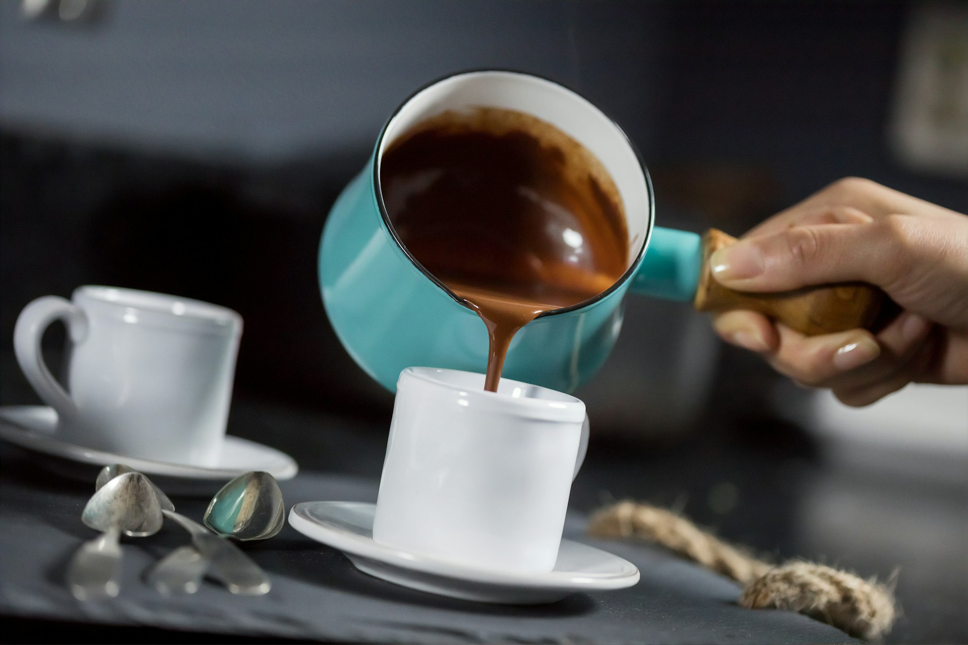 person pouring brown liquid on white ceramic cup